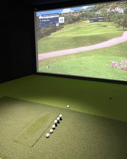 A hitting bay at FlagShots in Dunedin, FL, with balls on the turf in front of the projected impact screen